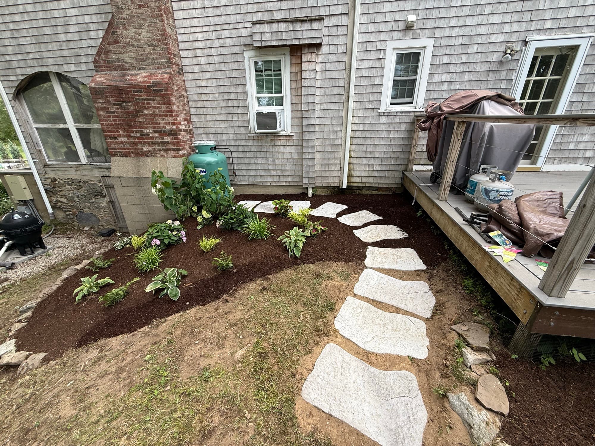 Freshly mulched planting bed with hostas and a stepping-stone path